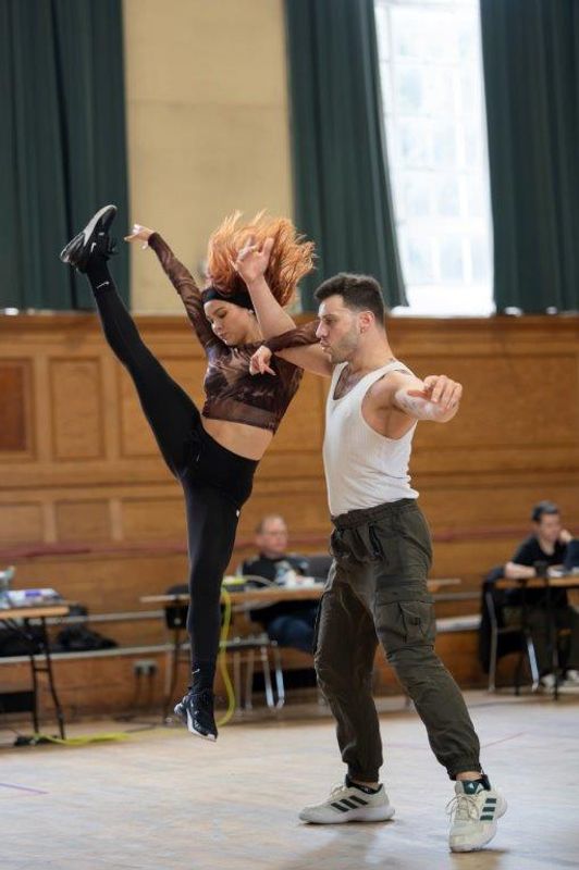 Two dancers and one is jumping up and kicking a leg up in the air
