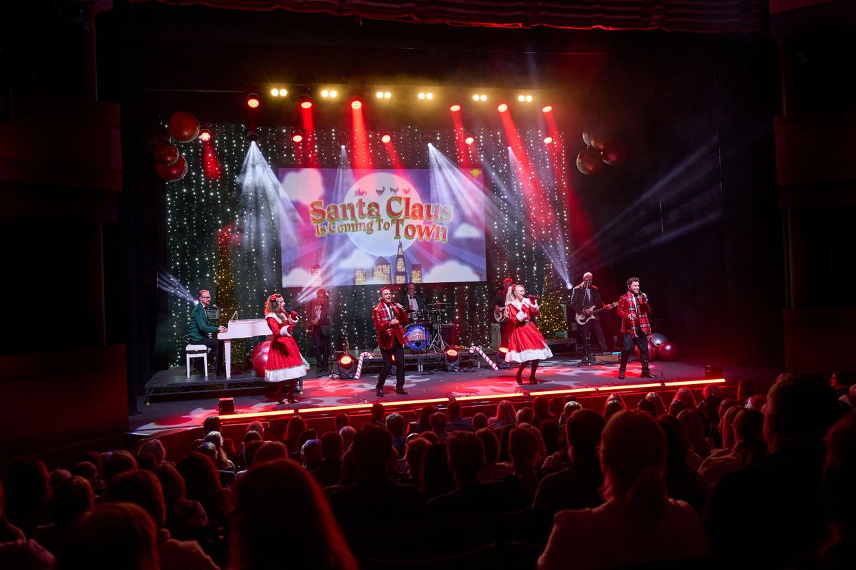 Performers on stage singing and dancing in a Christmas scene