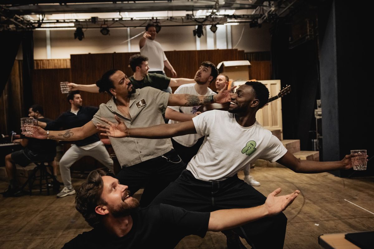 Group on men in a pub like setting, dancing and singing