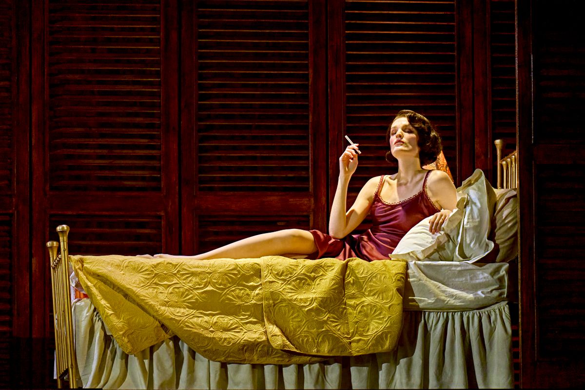 A person in a red nightdress lounges on a bed.