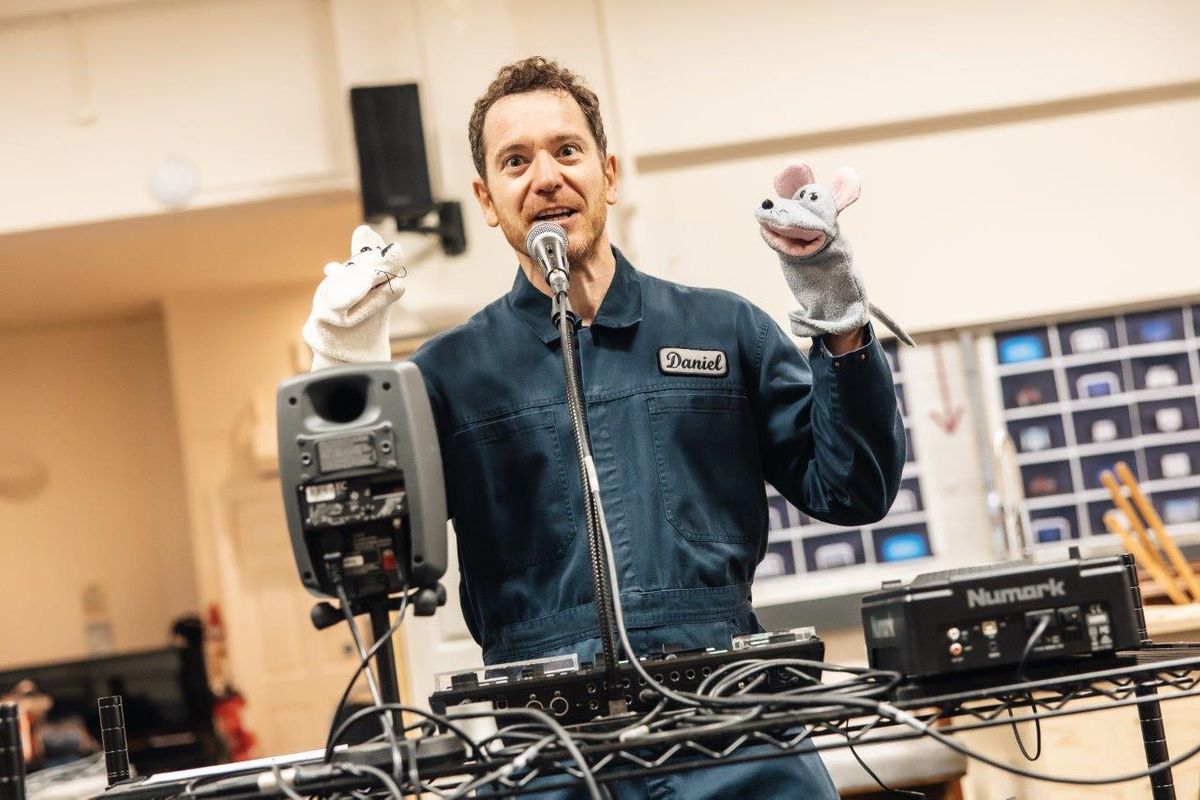 A person stood by a microphone with sock puppets on their hands