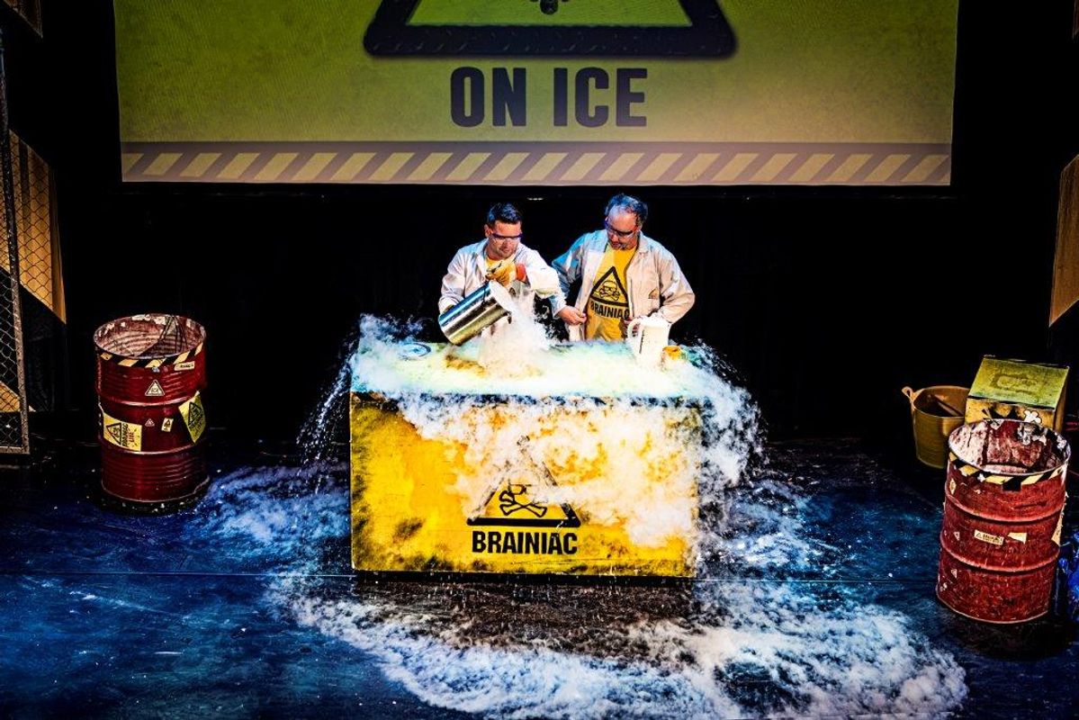 Two people  pour dry ice over a large yellow table.