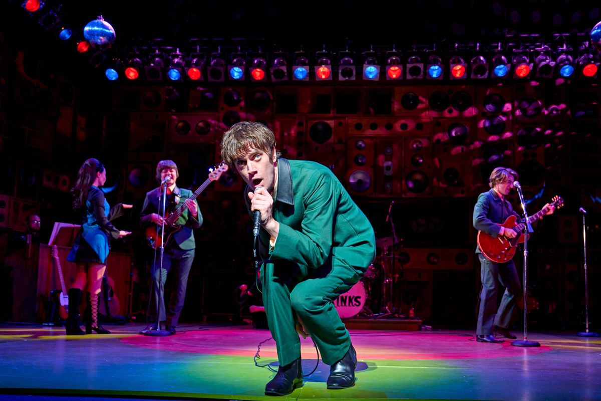 The lead singer crouches to the front of the stage.