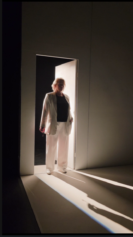 A person stood in a lit doorway and casts a shadow across the room