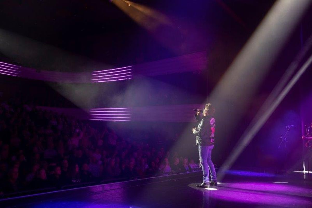 A persons sings on stage looking out to the audience.