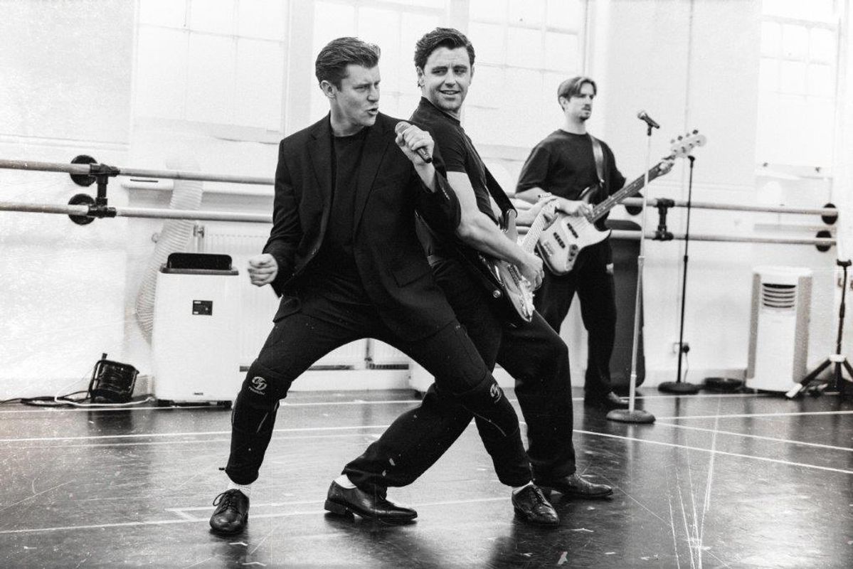 Black and white image of cats members rehearsing for Jersey boys. They are all wearing black and in a rehearsal studio