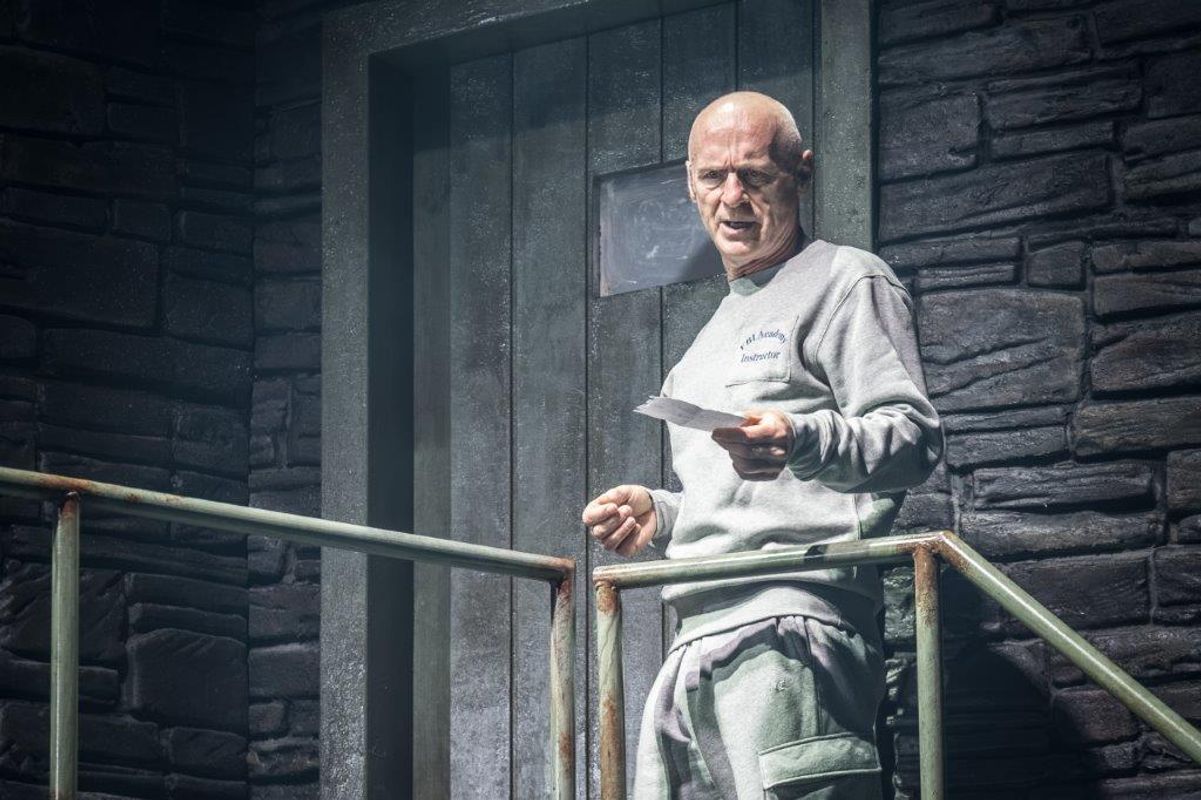 A man is stood at the top of a stairwell holding a piece of paper