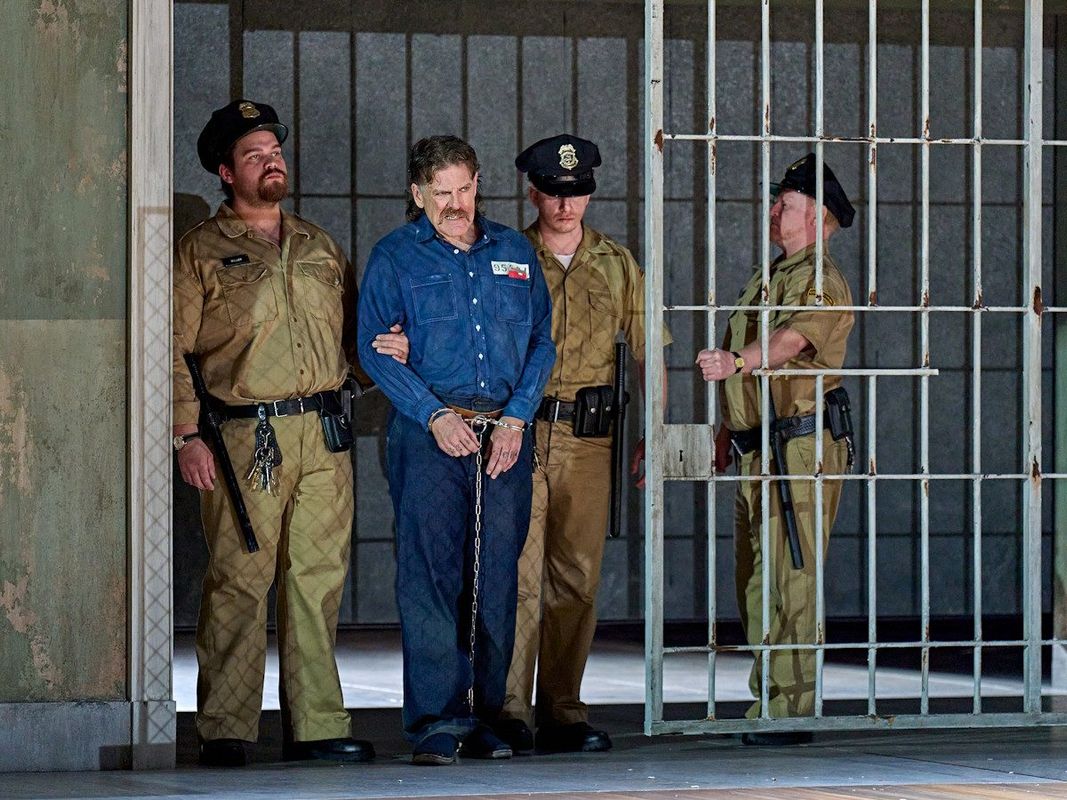 Two prison guards are escorting an inmate through a cell door