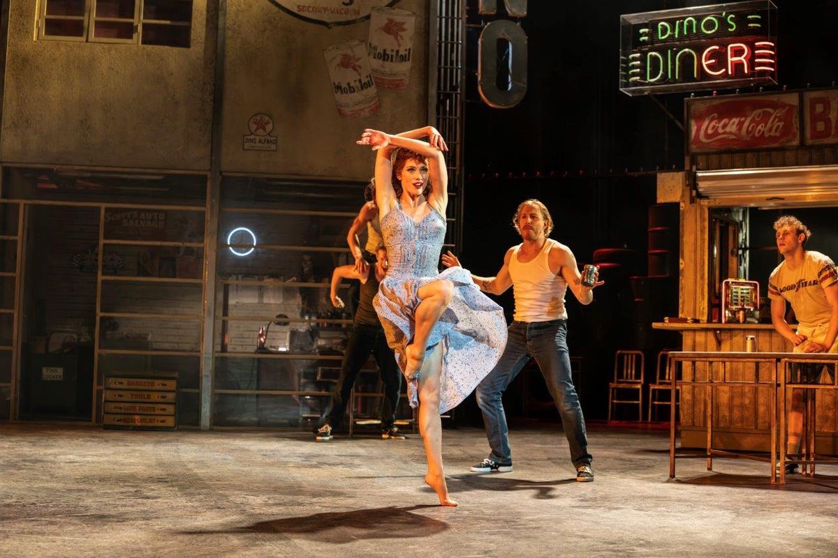 A lady dancing and people are watching around her. They are in a old styled bar setting
