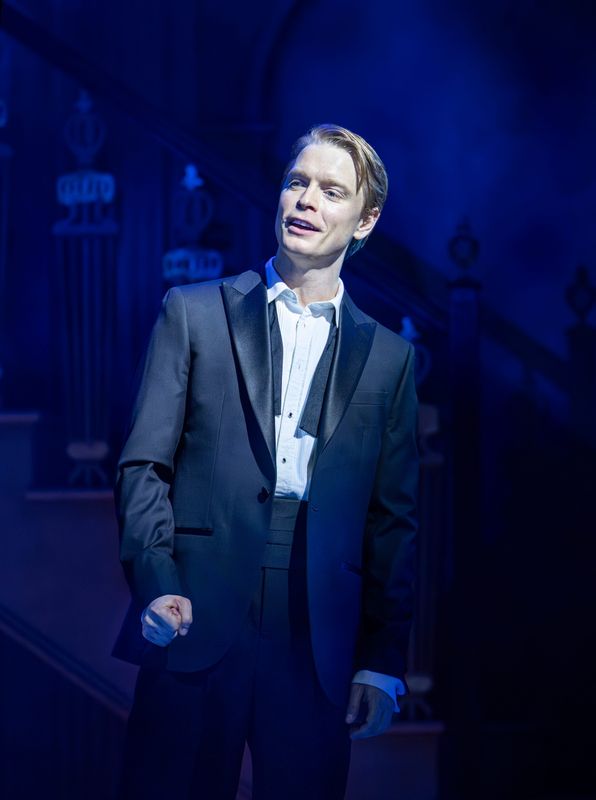 Male cast member in smart dress on the stage set of High Society.