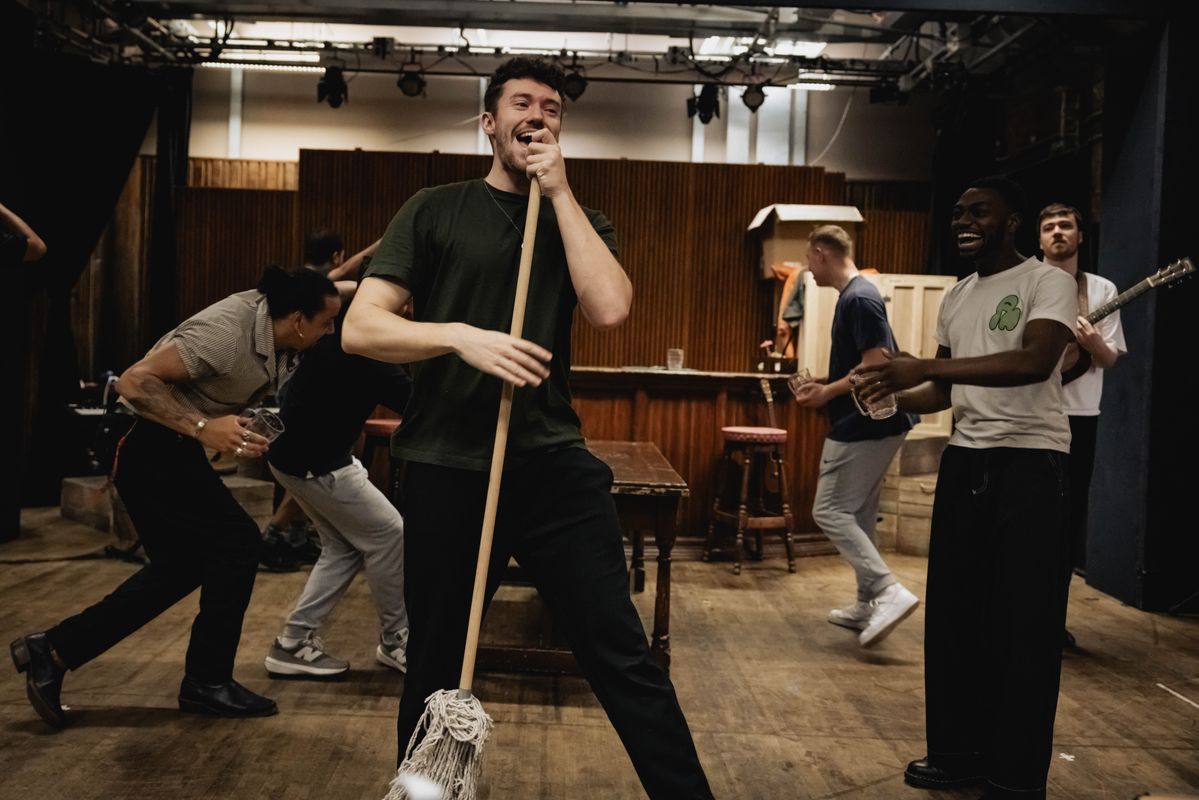 Group on men in a pub like setting, dancing and singing