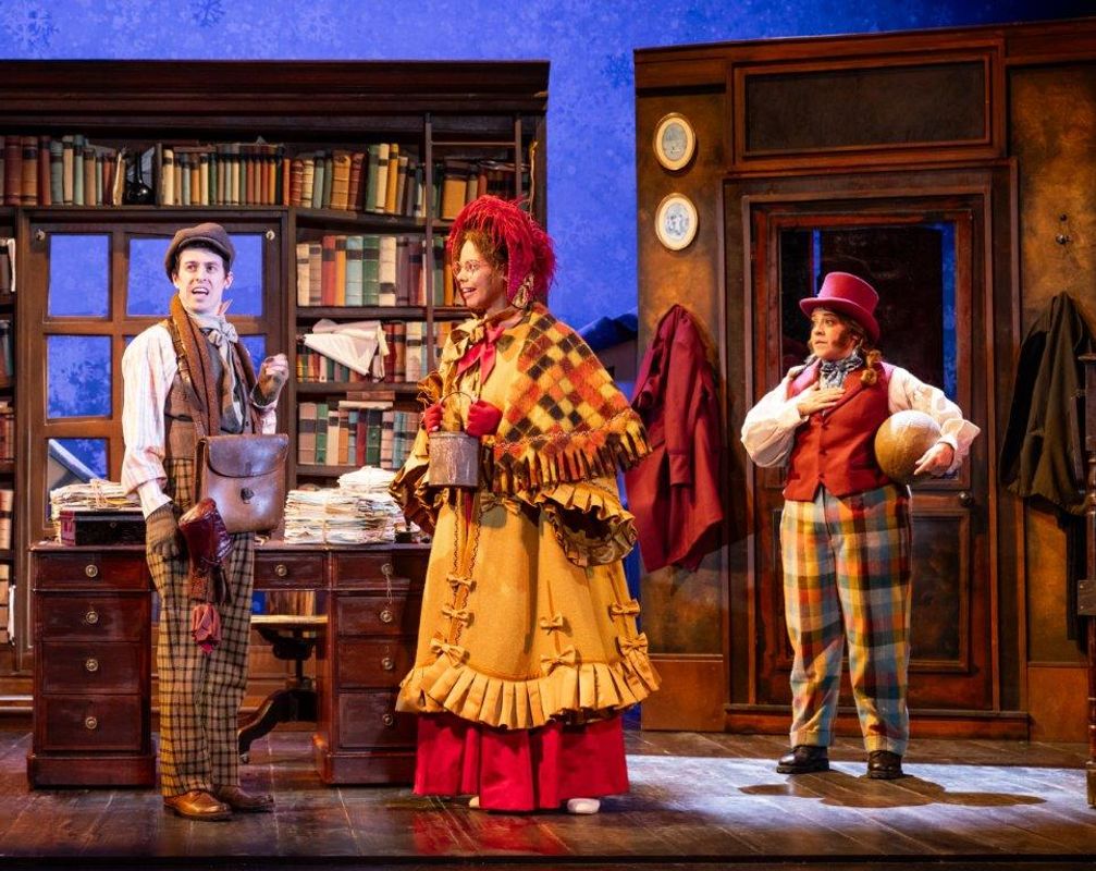 Three people stand on stage looking surprised.