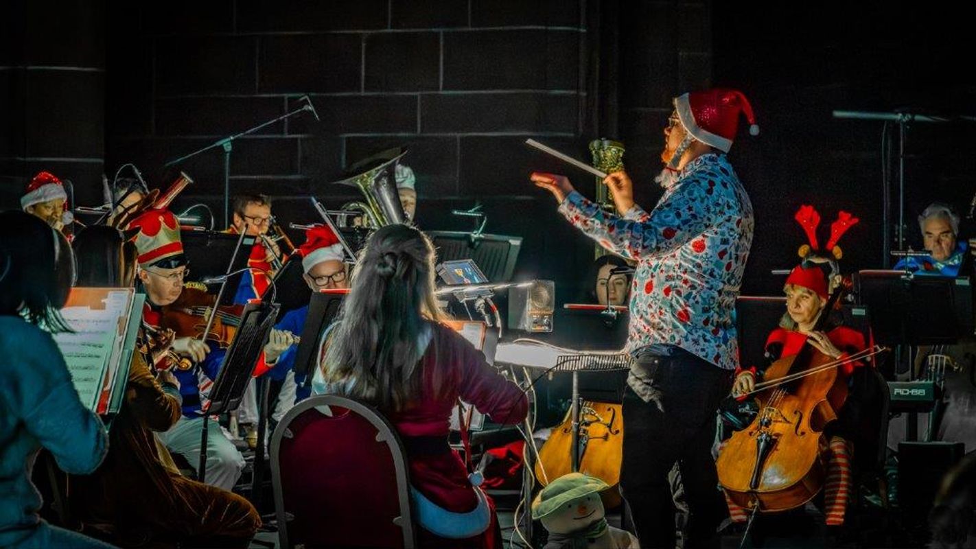 People performing on stage with The Snowman on a projector behind them.