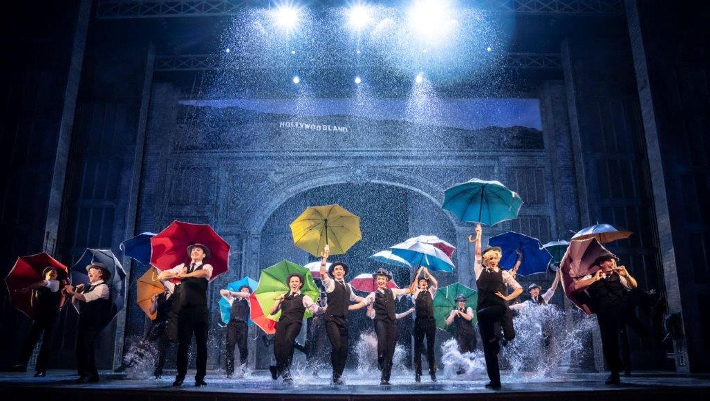 A group of people dancing in the rain and they are all holding a different colour umbrella
