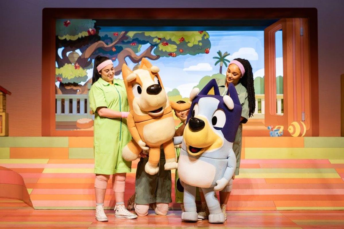 Bluey holds bingo in front of a tree.