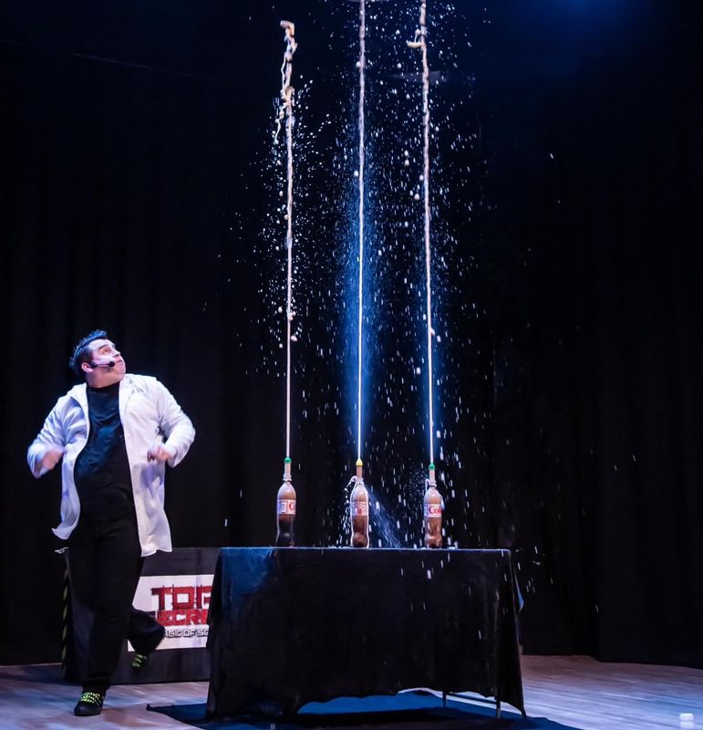 Three coca cola bottles shoot liquid into the air.