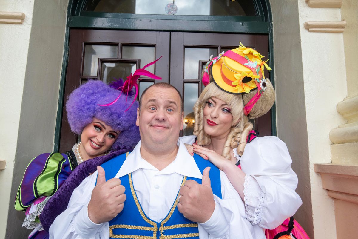 Buttons and the stepsisters stand outside the Theatre Royal entrance pulling faces to the camera.