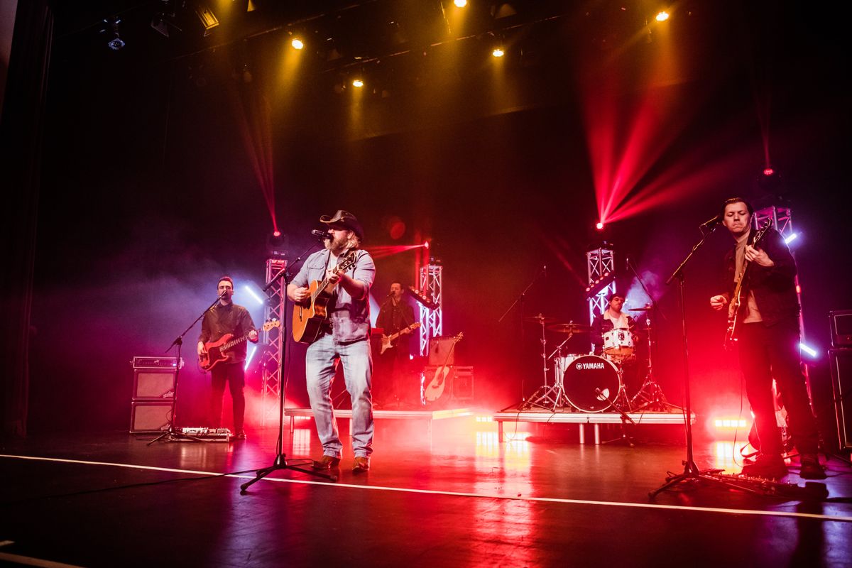 A person wearing a cowboy hat plays guitar.