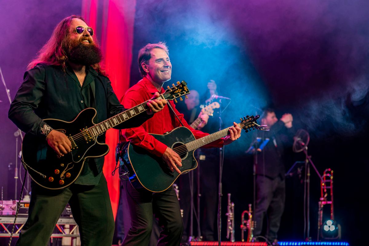 Two people play guitars on stage.