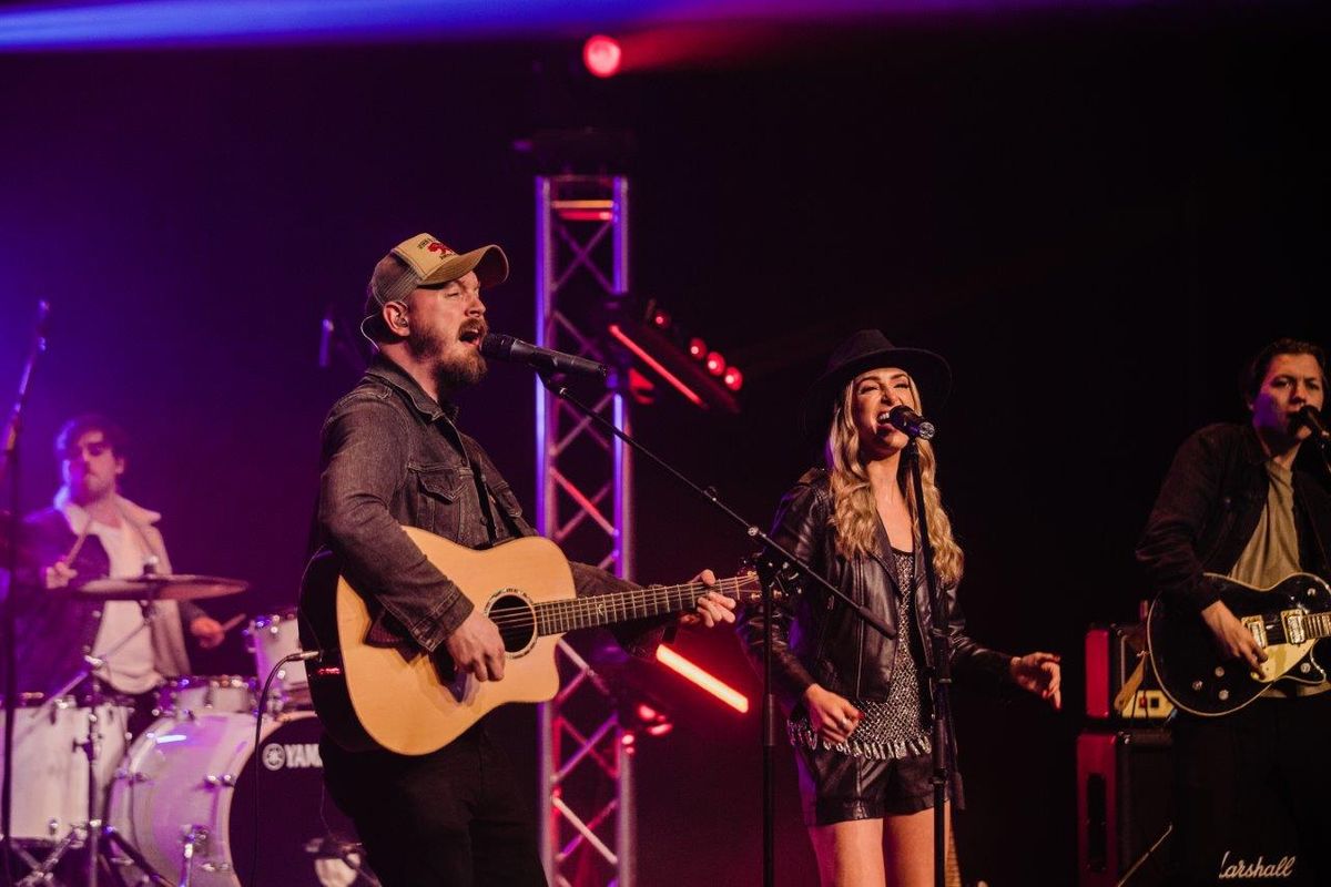 Country singers performing on stage wearing cowboy hats and playing instruments