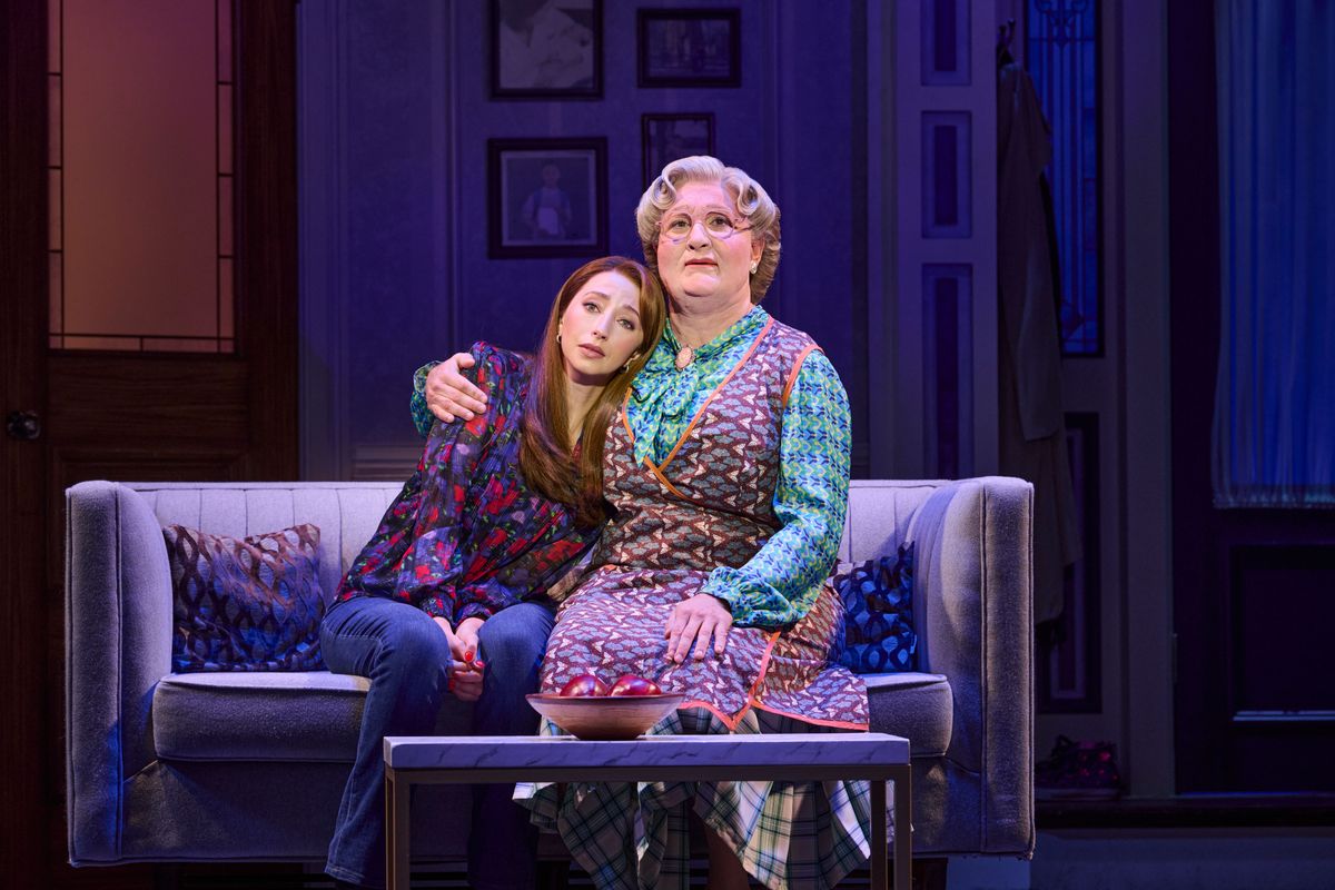 Mrs Doubtfire cuddles Miranda on a sofa.