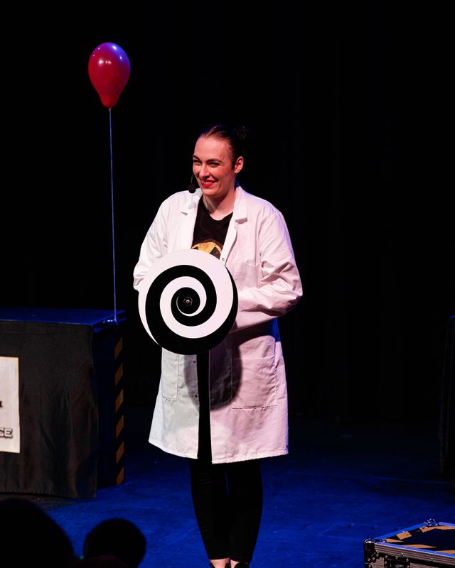 A person stands holding a black and white spiral wheel.