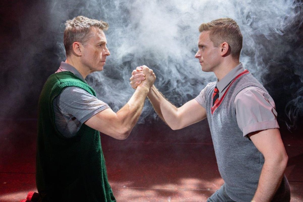 Two boys are facing each other and holding each others hand