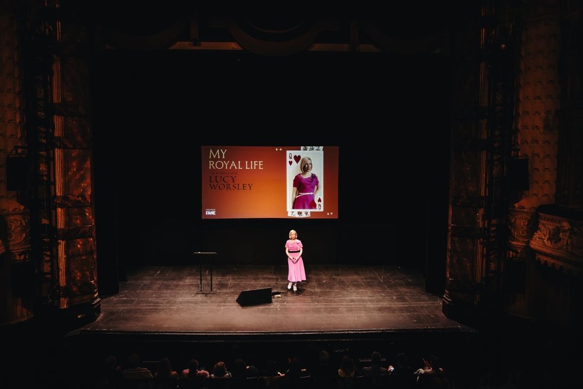 Lucy Worsley talking on stage. She is wearing a pink dress.