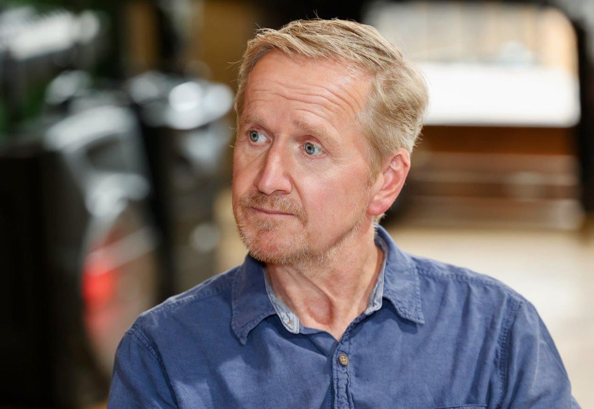 A man in a blue shirt, he looks off to the side