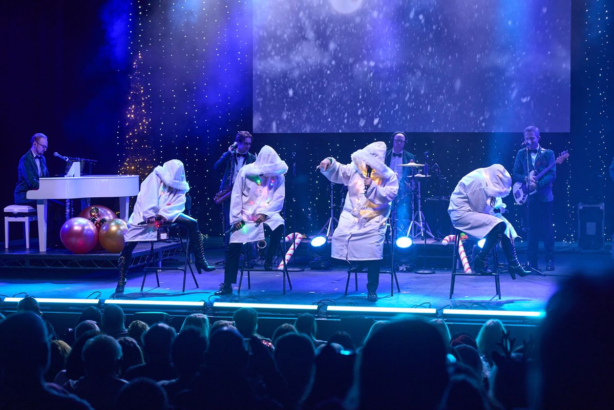 Performers on stage singing and dancing in a Christmas scene