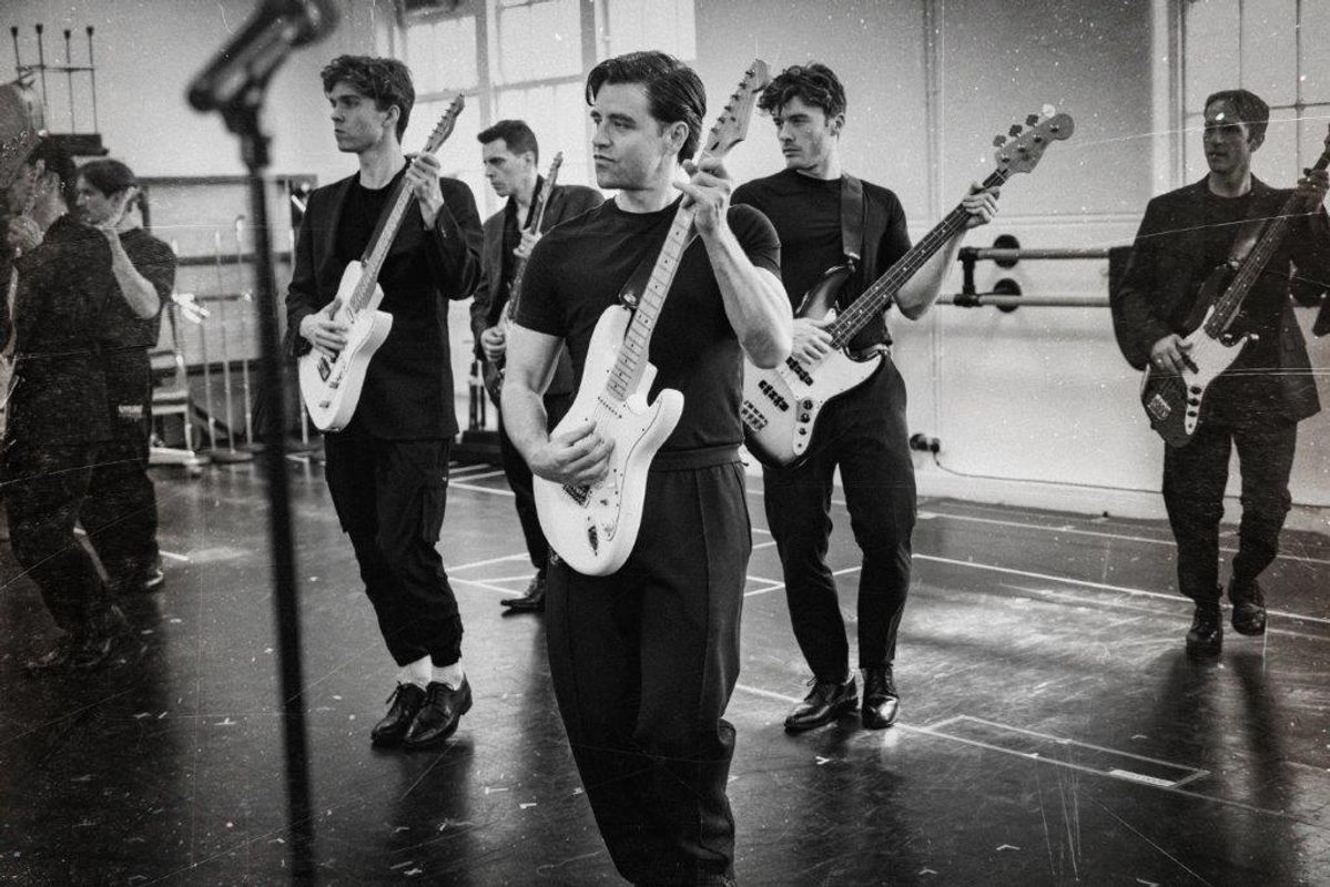 Black and white image of cats members rehearsing for Jersey boys. They are all wearing black and in a rehearsal studio