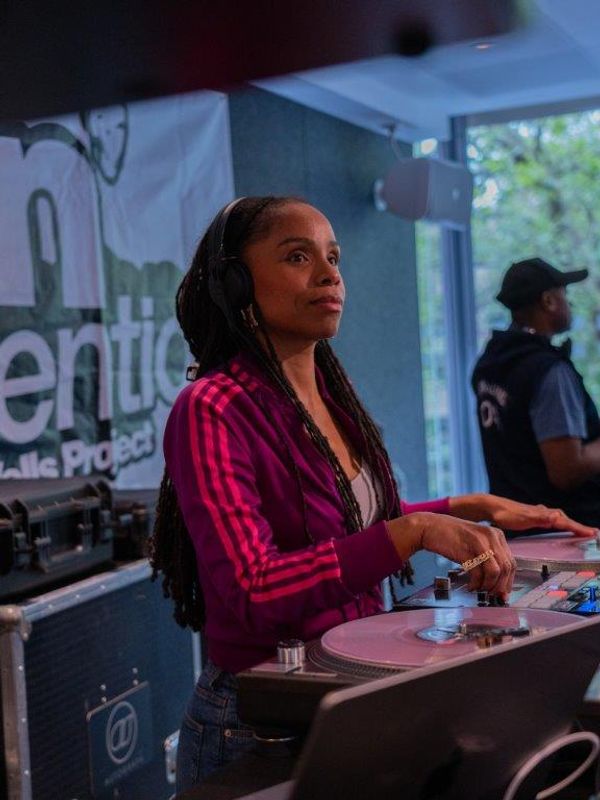 A person wearing  a purple tracksuit top uses the DJ decks.