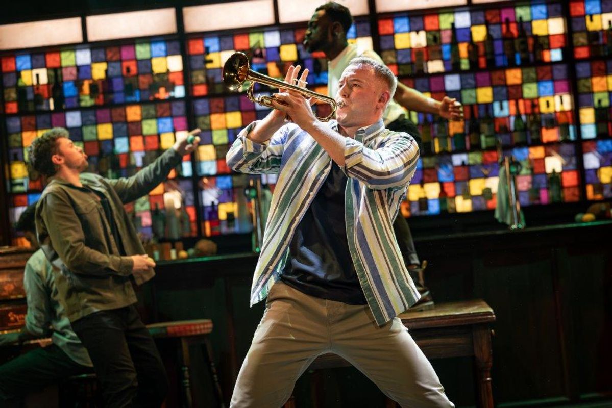 A person is playing the trumpet and two people in the back are dancing