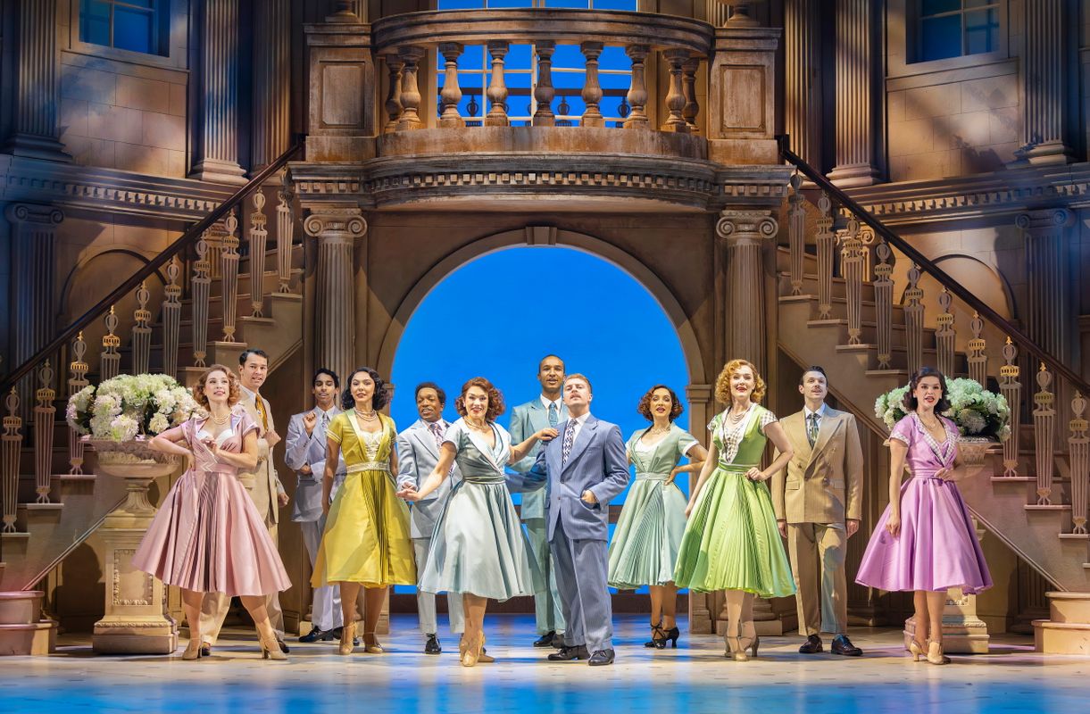 Male & female cast members of High Society posing on stage.