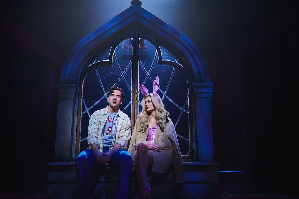 Two Legally Blonde cast members sat talking in front of a gothic style window.