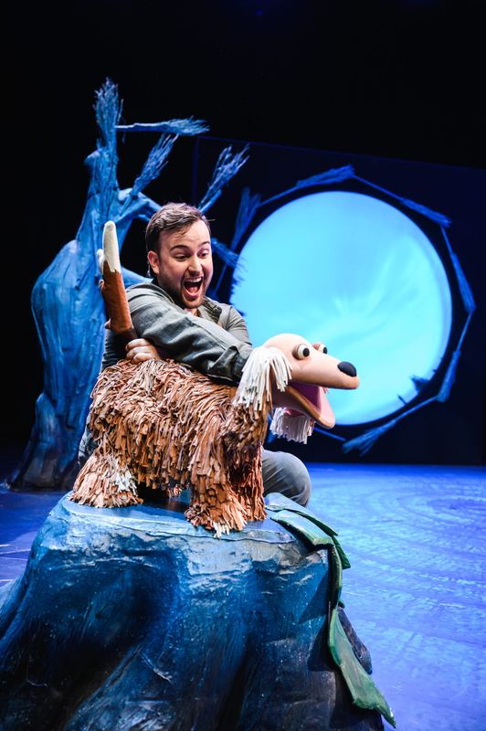 Actor onstage holding an animal puppet.