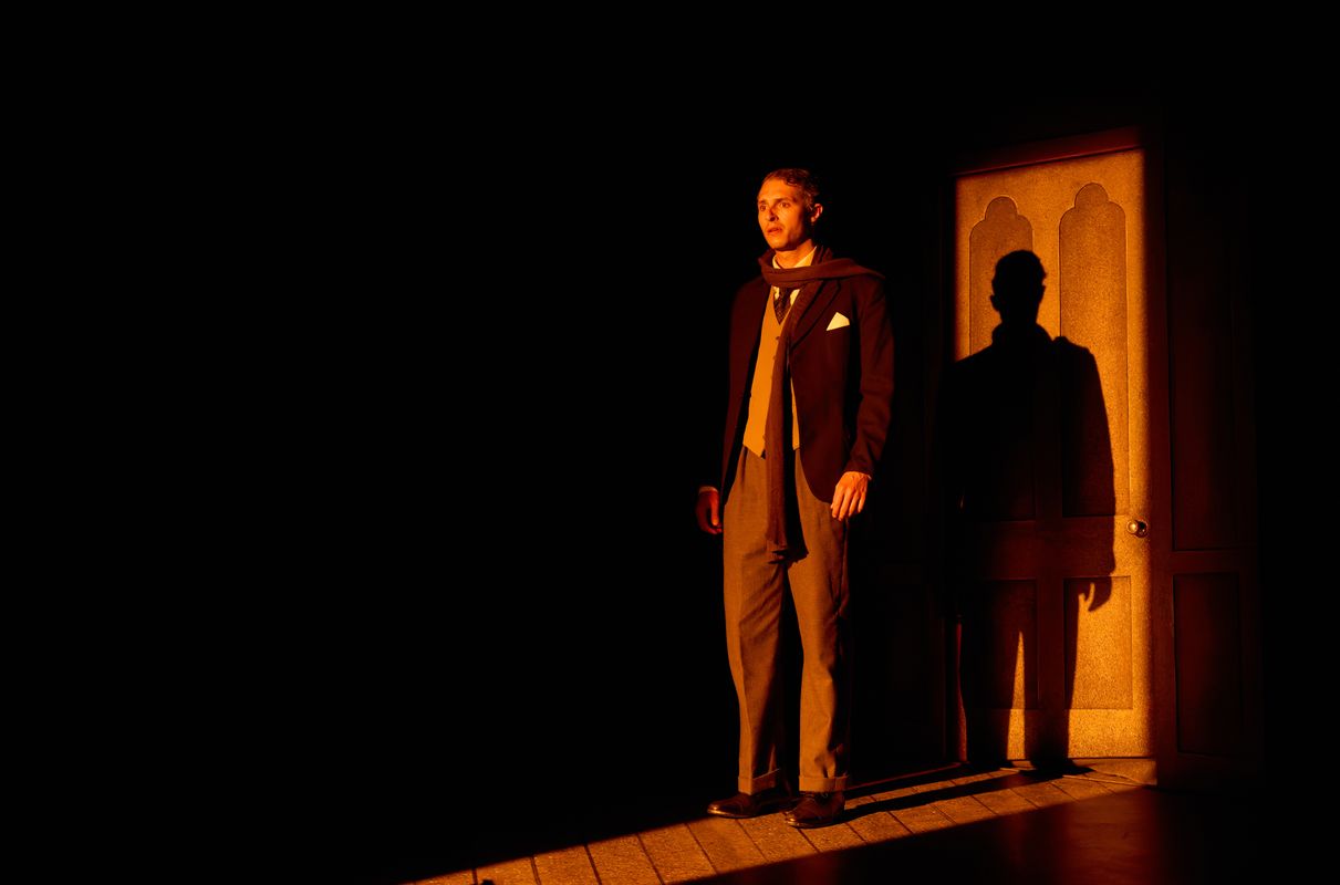 A person stands with their shadow on the door behind.