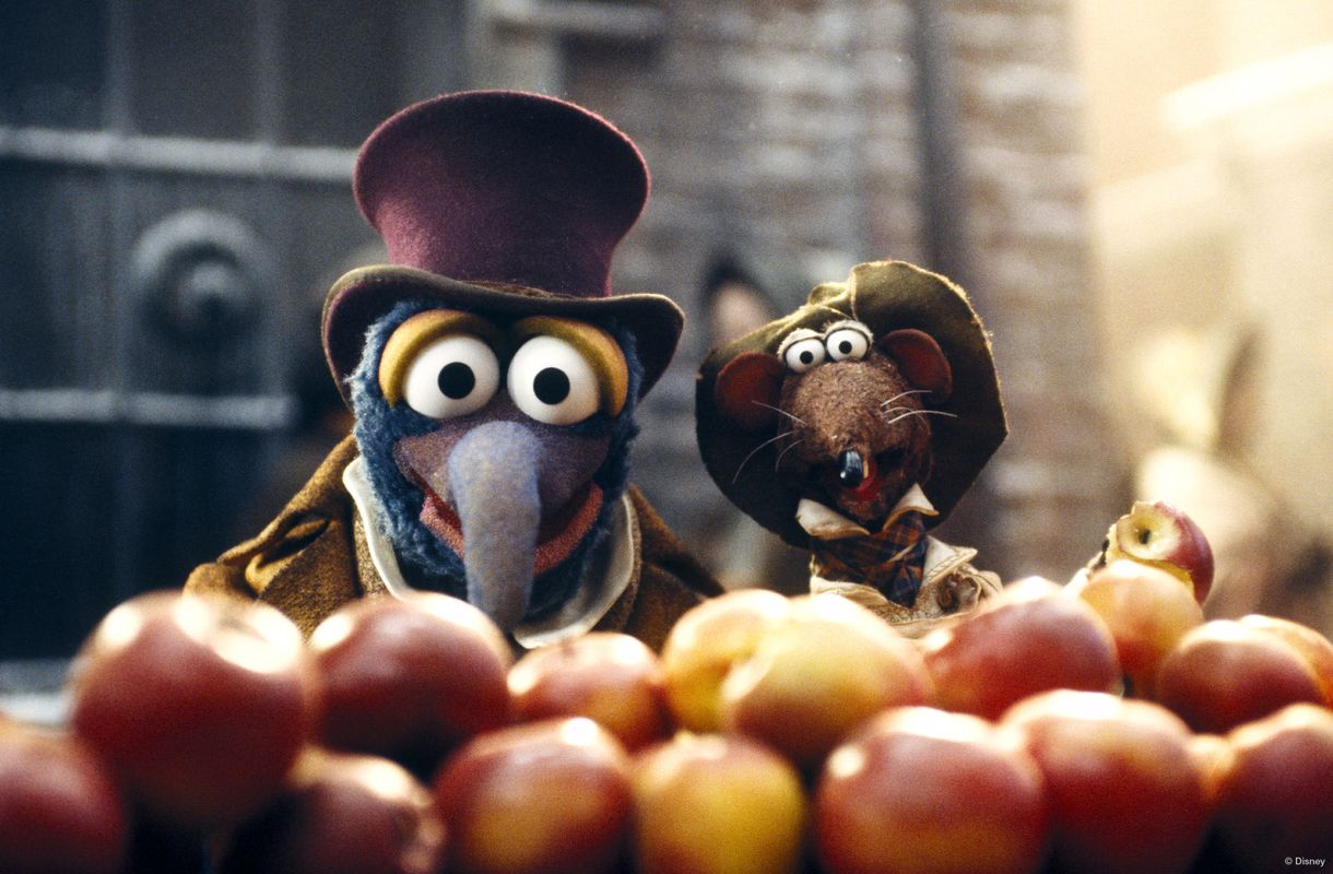 Two puppets are stood behind a pile of apples