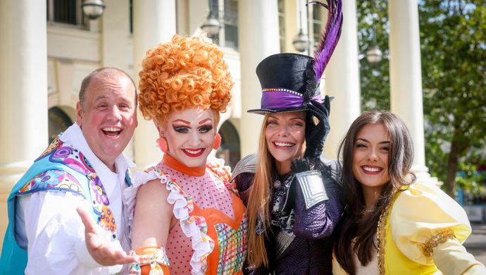 Four actors stand on the Theatre Royal forecourt posing in costume.
