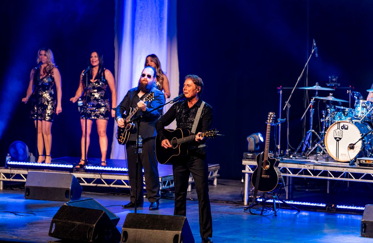 Two people dressed in black play guitars.