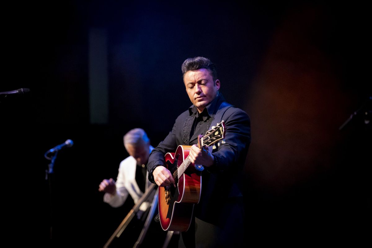 A person dressed in black plays guitar.