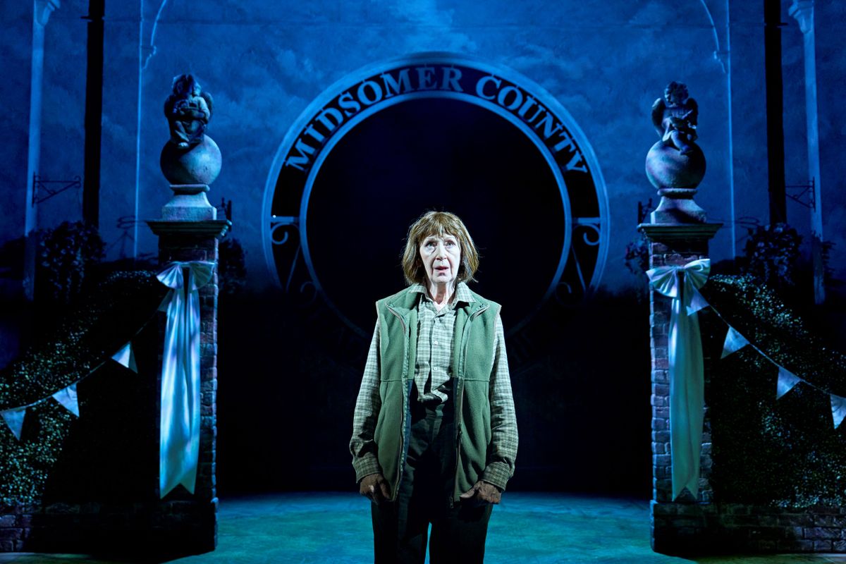 A person wearing a green gilet stands centre stage.