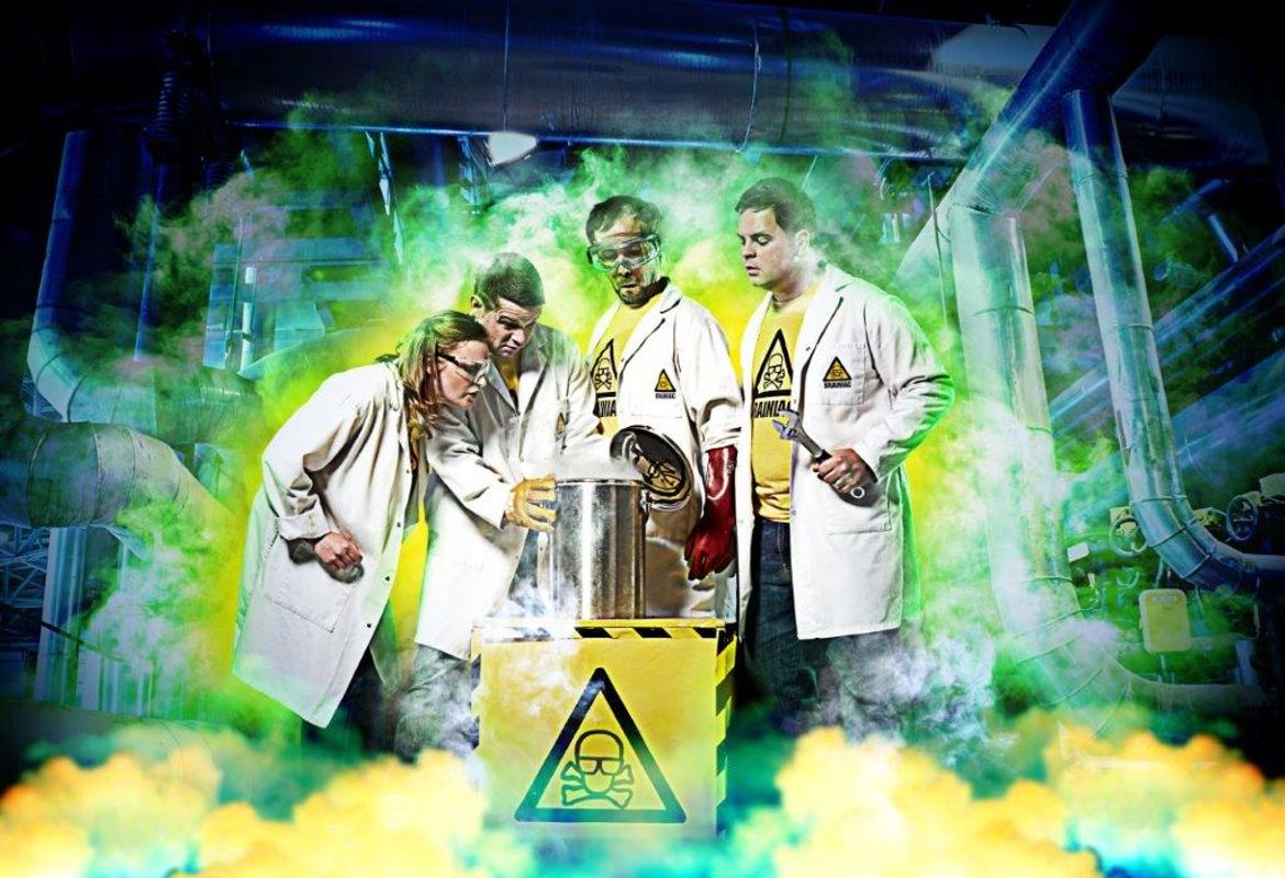 Four people in white lab coats look over a metal pot of dry ice.