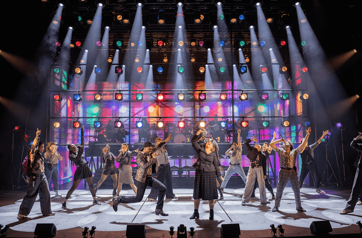 People singing and dancing on stage with bright lights