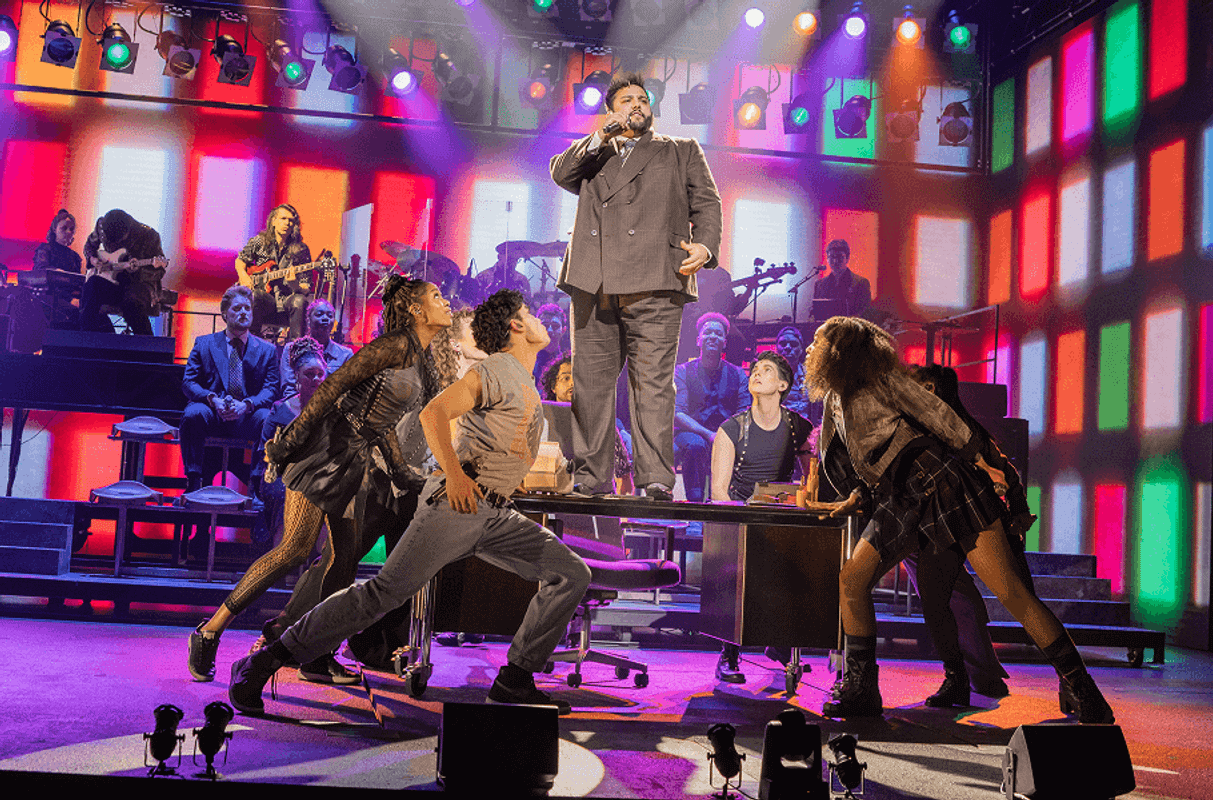 Someone stood singing on a desk and people dancing around them