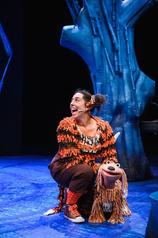 Actor on stage with a dog puppet.