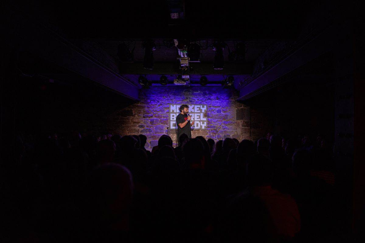 An audience watches Nish on stage.