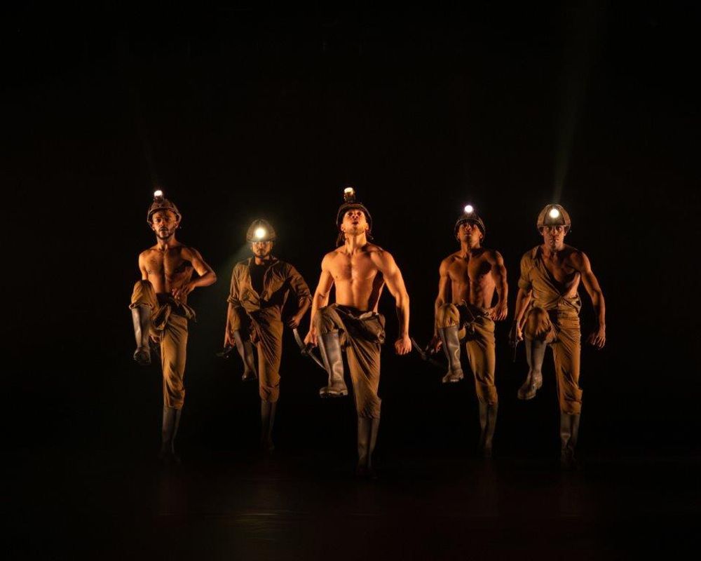 Group of dancers on stage wearing hard hats with lights on them