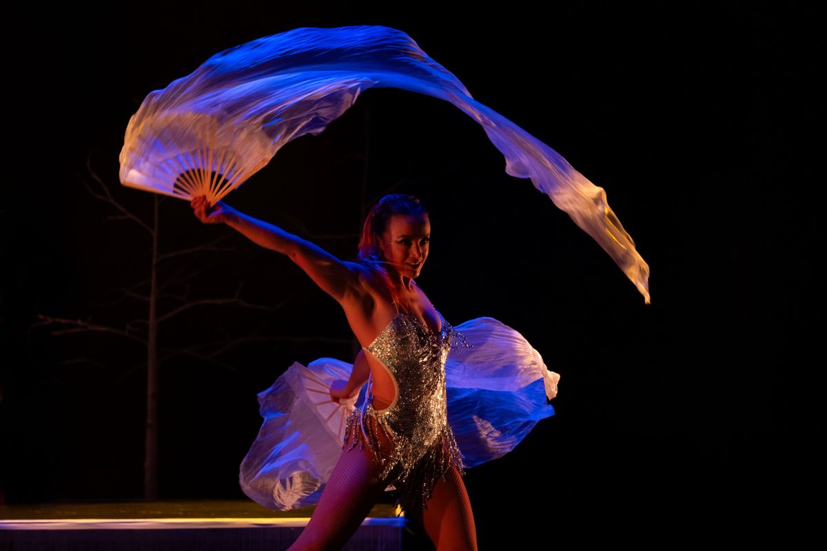 A circus performer uses a fan.