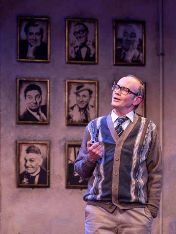 A man wearing glasses is sat in a dressing room backstage setting